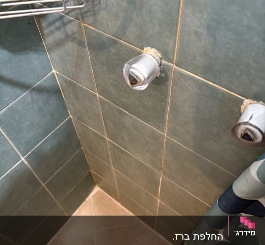 ברזים על קיר אריחים בחדר אמבטיה